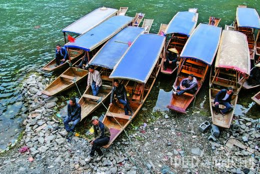 4月12日,湖南凤凰,在沱江下游等待载客的农家船。当地船夫表示,往年此时前来乘船的游客众多,现今10块钱的船资也很难寻觅到游客,大家只好在岸边聊天下棋。摄影/本刊记者 杨华峰